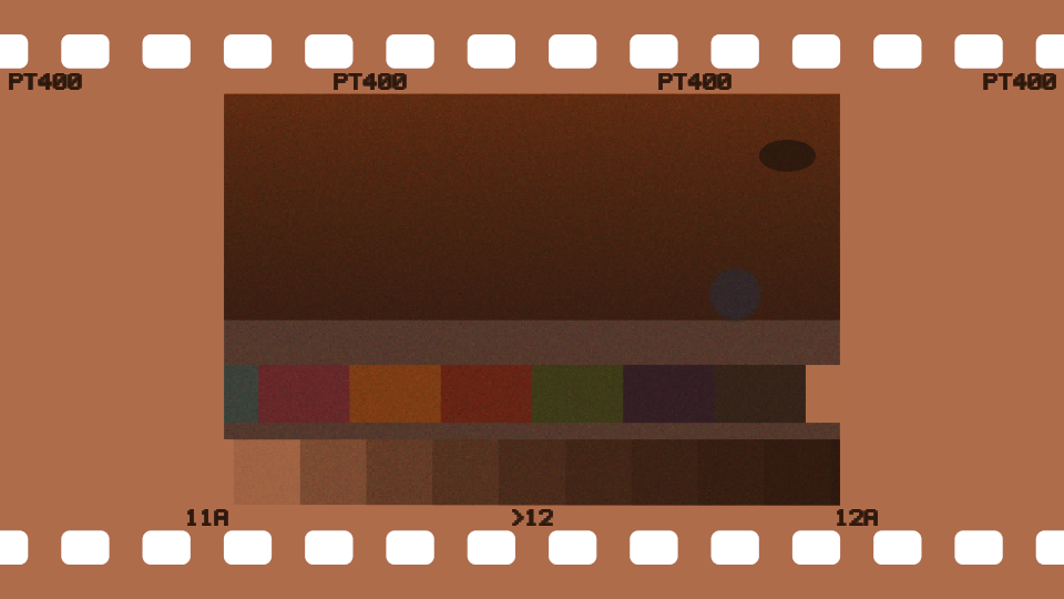 The same card as the negative itself on a light box: an orange strip with clear sprocket holes, dark edge print, and the picture inverted and orange