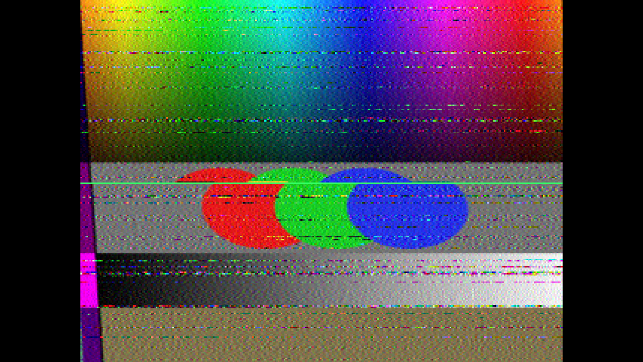 A test card received over a fading HF path: the new picture overwriting the old from the top with a green cursor on the arriving line, a slant from a receiver clock 60 ppm off, noise streaks, and a colour fringe down the left edge where the slant has pulled the end of one scan into the start of the next